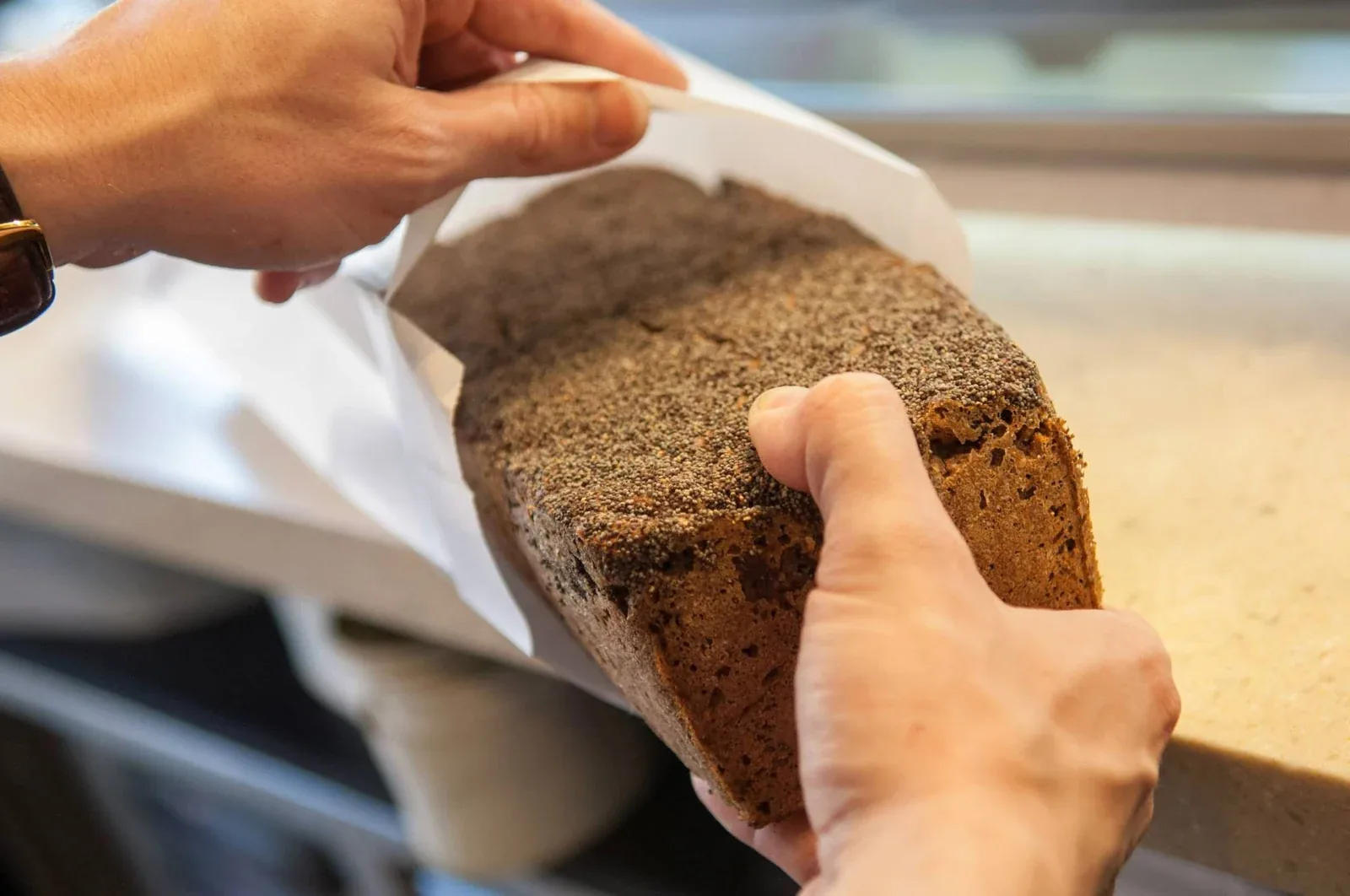 Bagerens hænder arbejder med et brød ved bagerbordet