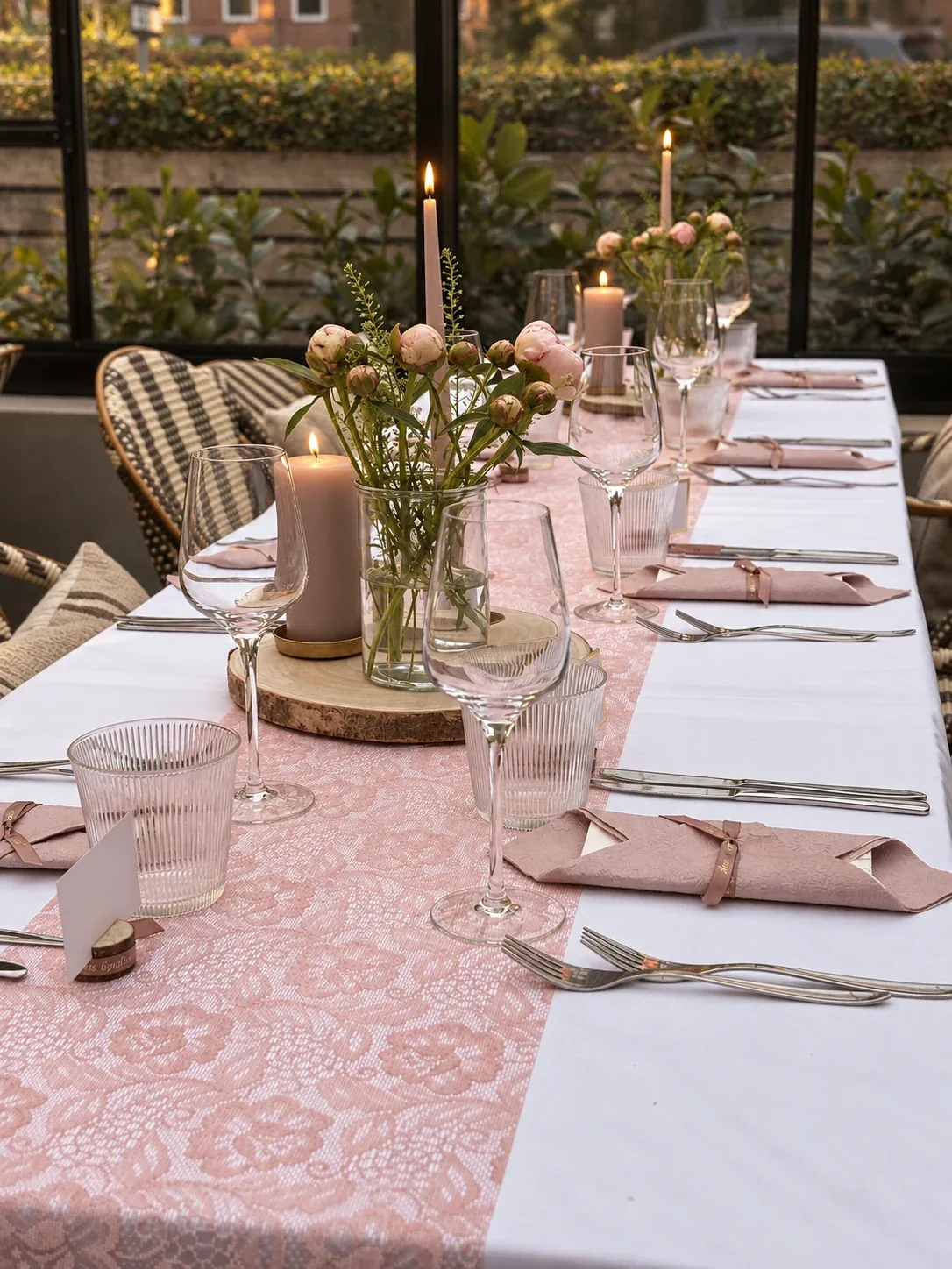 Et elegant dækket selskabsbord med rosa detaljer, blomster og levende lys i Orangeriet
